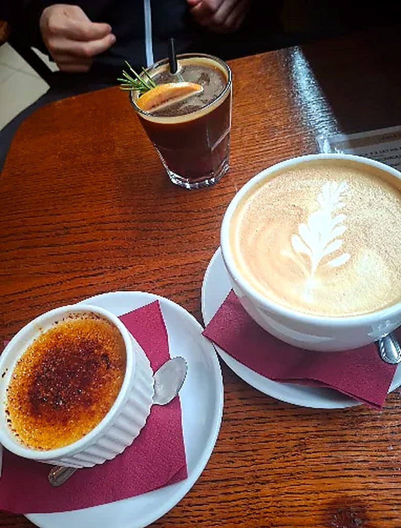 Cappuccino z latte art, creme brulee i mrozona kawa na stole